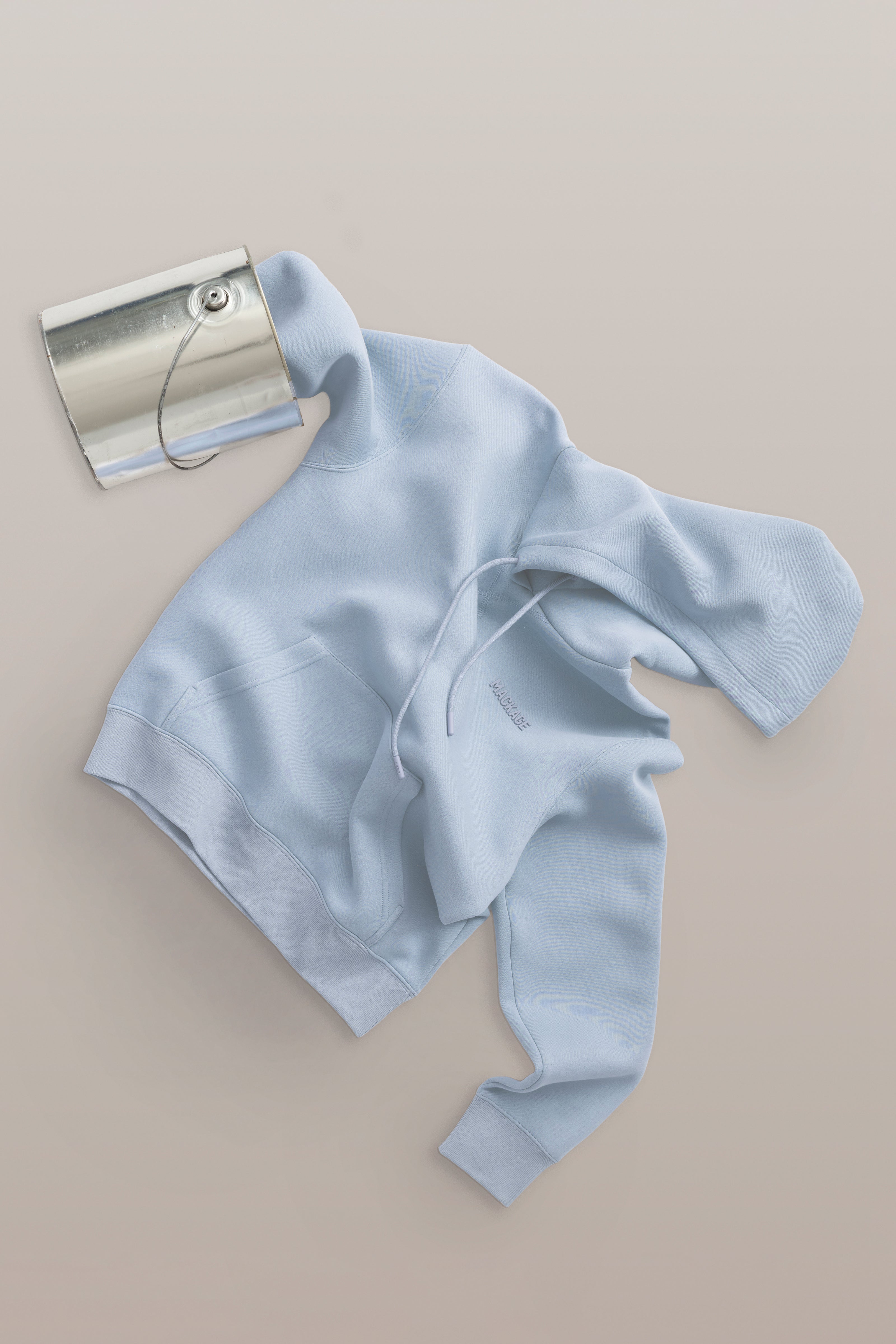 Light blue knitted headband with a silver clutch on a beige background